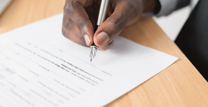 right hand holding a pen, signing a document